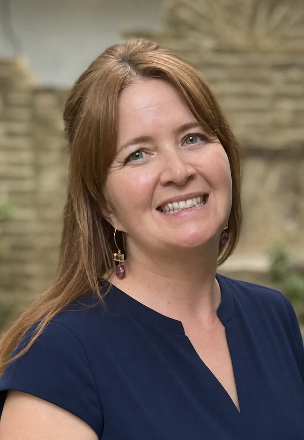 A blonde haired woman wearing a dark blue blouse