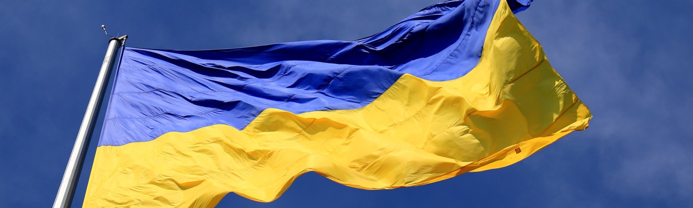The Ukraine flag, flapping in the breeze against a blue, lightly cloudy sky