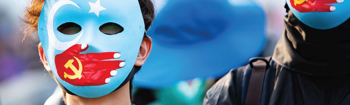 Person with East Turkestan flag face mask with a hand of the People's Repbulic of China flag covering their mouth