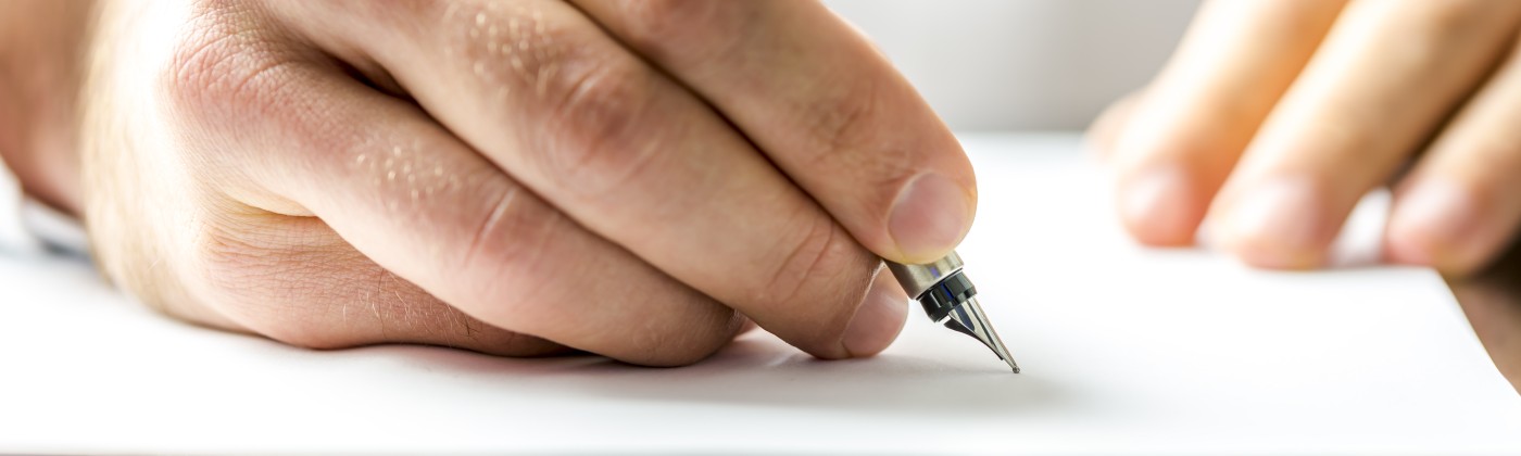 closeup of a hand holding a pen signing a document