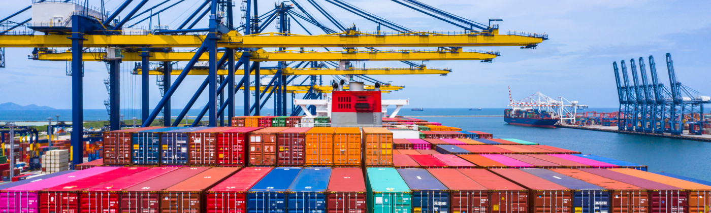 Brightly colored Cargo containers at a port, with tall cranes in the background