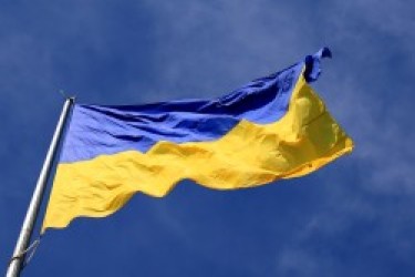 The Ukraine flag, flapping in the breeze against a blue, lightly cloudy sky
