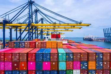 Brightly colored Cargo containers at a port, with tall cranes in the background